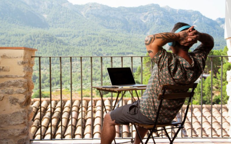 handsome-man-relaxing-working-laptop-balcony-his-house-while-listening-music-enjoying-mountain-views_109656-631